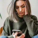 woman looking at phone frustrated